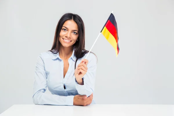 Businesswoman sitting at the table and holding germany flag — Stock Photo, Image
