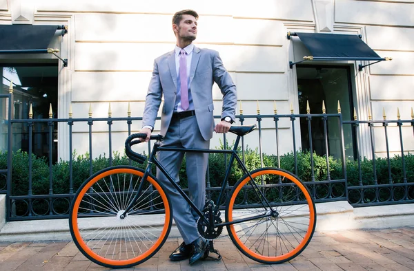 Бізнесмен стоїть з велосипедом на відкритому повітрі — стокове фото