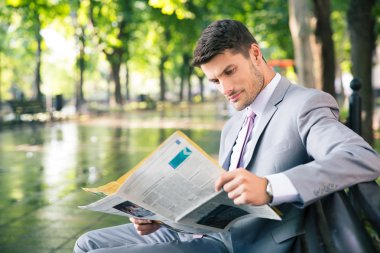 İş adamı dışarıda gazete okuyor.