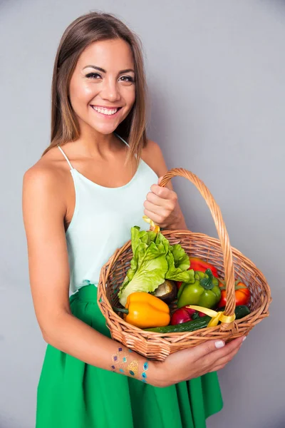 Femme souriante tenant panier avec des légumes — Photo