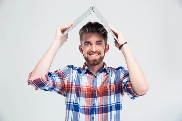 Hombre sosteniendo portátil en su cabeza como el techo de la casa —  Fotos de Stock