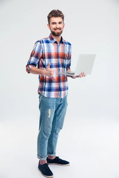 Homem de pé com laptop e mostrando sinal de polegar para cima — Fotografia de Stock
