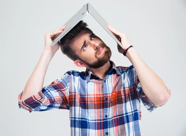 Man holding laptop on his head like roof of house — Stock Photo, Image