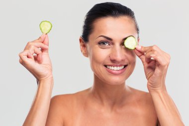 Happy woman covering her eye with cucumber