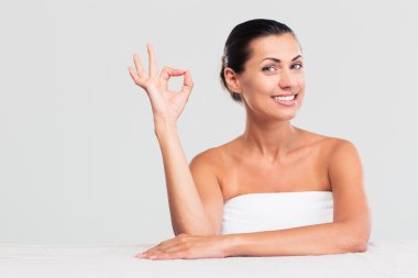 Woman sitting at the table in towel and showing ok sign