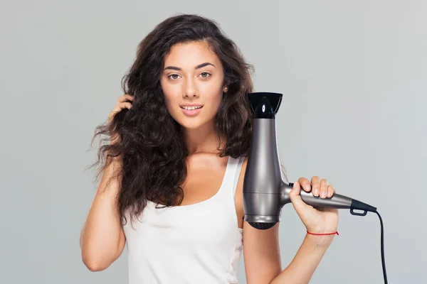 Feliz hermosa mujer sosteniendo secador de pelo —  Fotos de Stock