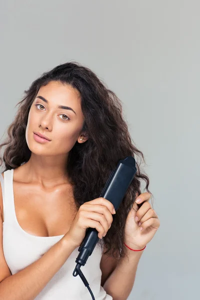 Woman doing hairstyle with hair straightener — Stock Photo, Image