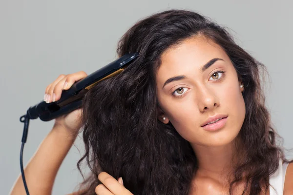 Mulher fazendo penteado com alisador de cabelo — Fotografia de Stock