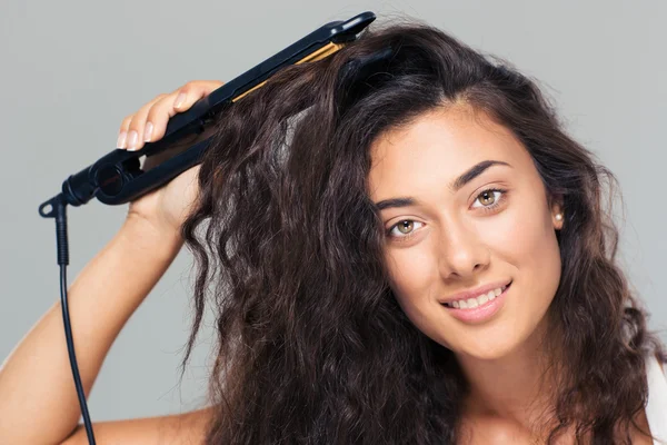 Mulher fazendo penteado com alisador de cabelo — Fotografia de Stock