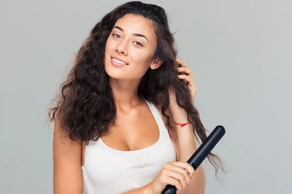 Woman doing hairstyle with hair straightener — Stock Photo, Image