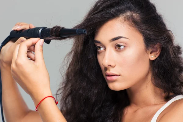 Mulher fazendo penteado com alisador de cabelo — Fotografia de Stock