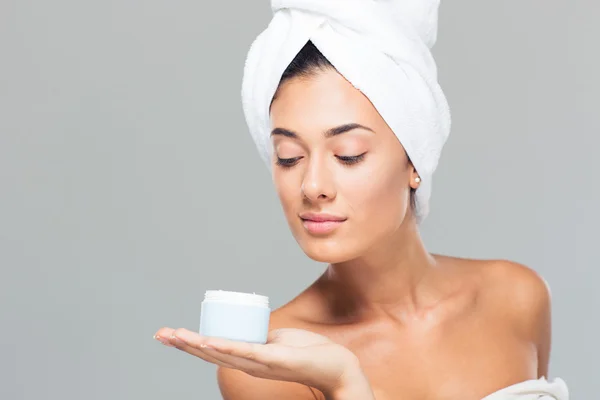 Женщина с полотенцем на голове держит банку крема — стоковое фото