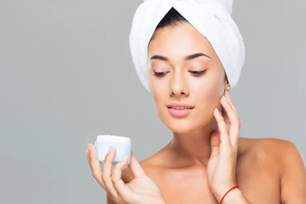 Woman with towel on head holding cream jar — Stock Photo, Image