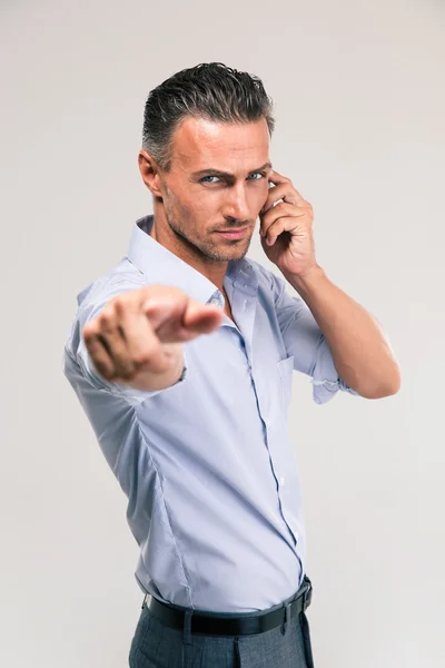 Businessman talking on the phone and pointing at camera — Stock Photo, Image
