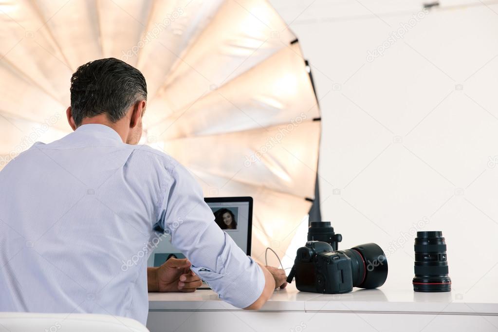 Back view portrait of photographer using laptop