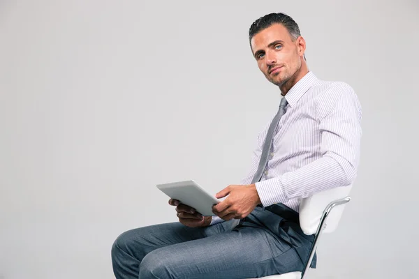 Бізнесмен сидить на офісному стільці з планшетним комп'ютером — стокове фото