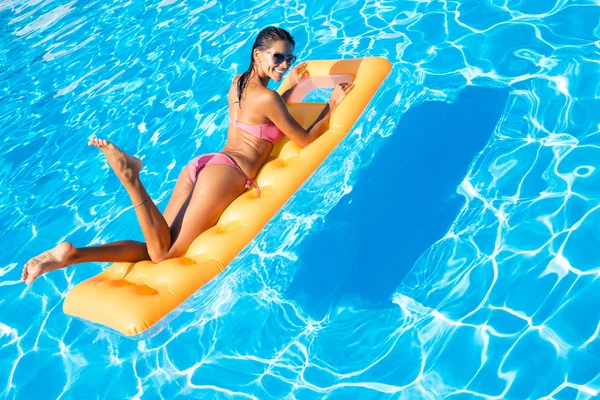 Kobieta leżąc na dmuchany materac w basenie — Zdjęcie stockowe