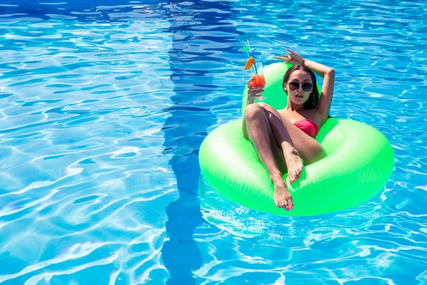 Femme couchée sur un matelas gonflable avec cocktail — Photo