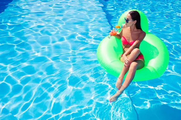 Woman drinking cocktail on air mattress — Stock Photo, Image