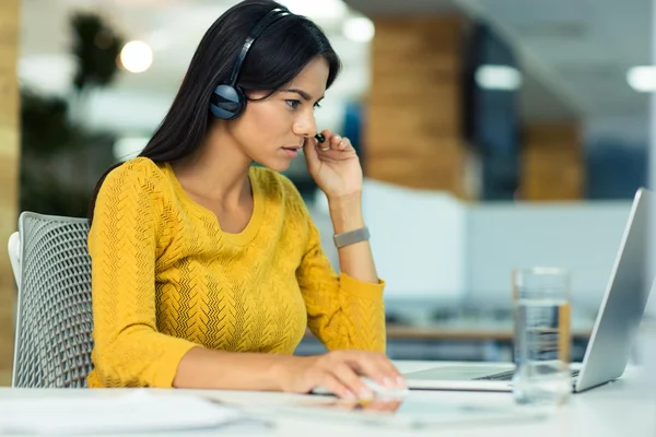 Affärskvinna i hörlurar använder laptop — Stockfoto