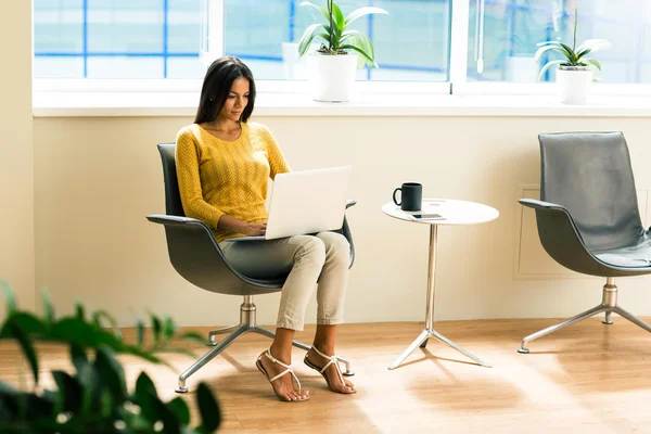 Affärskvinna sitter på kontorsstol och använder bärbar dator — Stockfoto