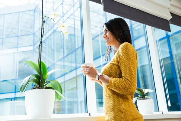 Donna d'affari che tiene la tazza con il caffè e guarda la finestra — Foto Stock