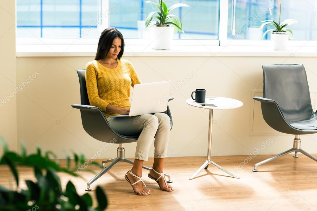 Businesswoman sitting on office chair and using laptop
