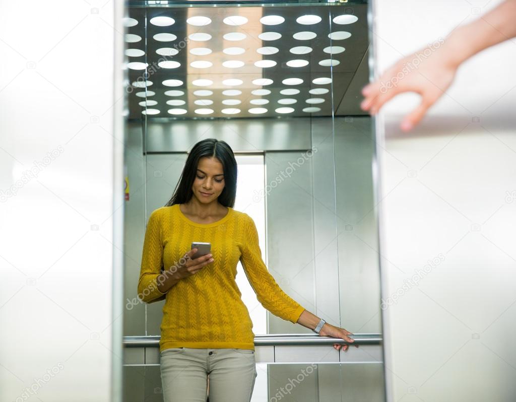 Businesswoman using smartphone in elevator