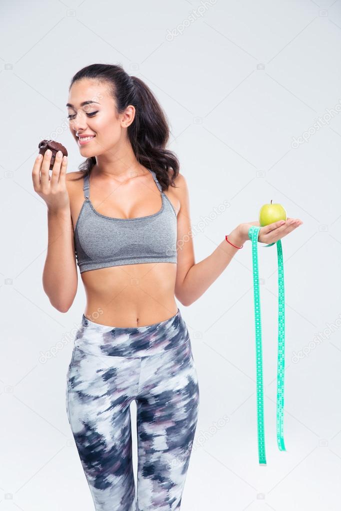 Happy girl choosing between apple and cake