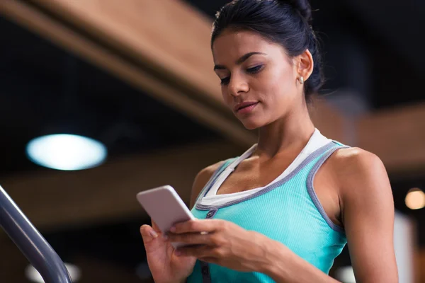 Vrouw met behulp van smartphone in fitness gym — Stockfoto