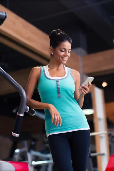 Frau nutzt Smartphone im Fitnessstudio — Stockfoto