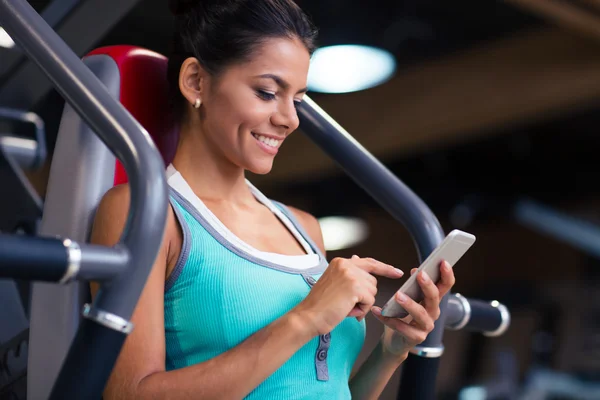 Vrouw met behulp van smartphone in fitness gym — Stockfoto