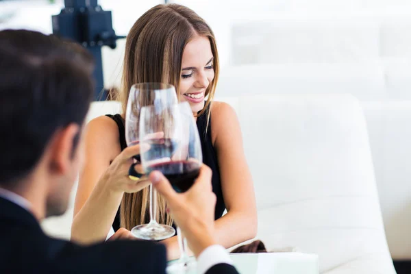 Мужчина с счастливой элегантной женщиной пьет красное вино — стоковое фото
