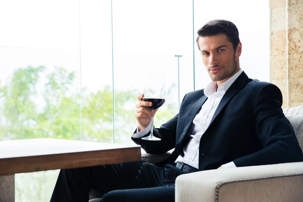 Бизнесмен сидит в ресторане с бокалом вина — стоковое фото