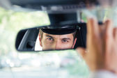 männlicher Chauffeur blickt auf sein Spiegelbild im Spiegel