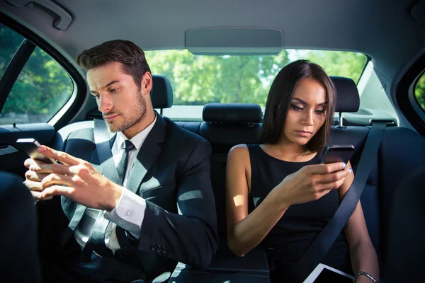 Бизнесмен и предпринимательница используют смартфон в автомобиле — стоковое фото