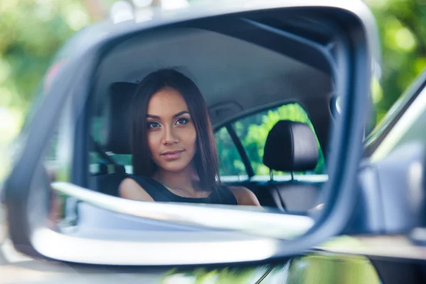 Frau blickt auf ihr Spiegelbild im Autospiegel — Stockfoto