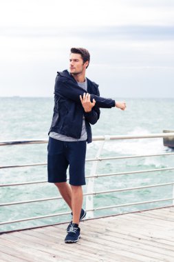 Yakışıklı spor adam açık havada eller germe