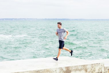 Plajda iskele üzerinde koşan adam