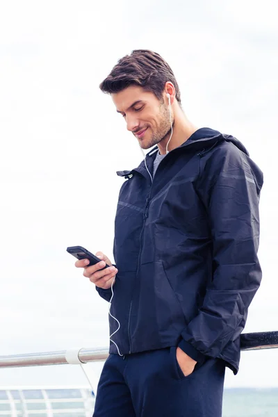 Uomo utilizzando smartphone con cuffie all'aperto — Foto Stock