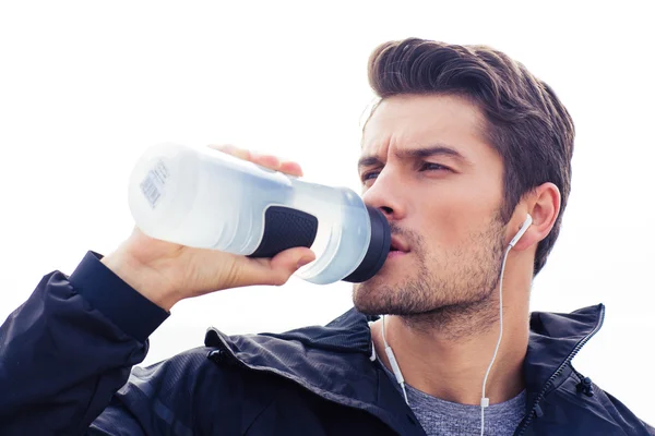 Schöner Mann mit Kopfhörern, der Wasser trinkt — Stockfoto