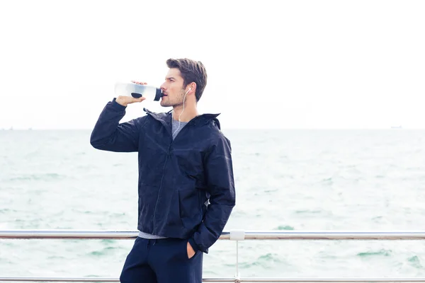 Man in headphones drinking water outdoors — Stock Photo, Image