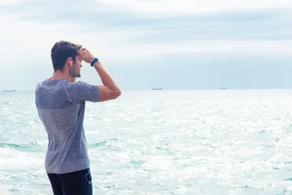 Homem de roupas esportivas olhando para o mar ao ar livre — Fotografia de Stock