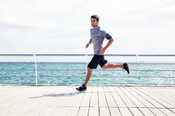 Hombre deportivo corriendo al aire libre cerca del mar — Foto de Stock