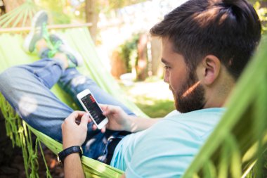 Hammok üzerinde yalan ve smartphone kullanarak adam