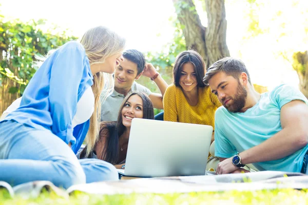 Friends using laptop together outdoors — Stock Photo, Image