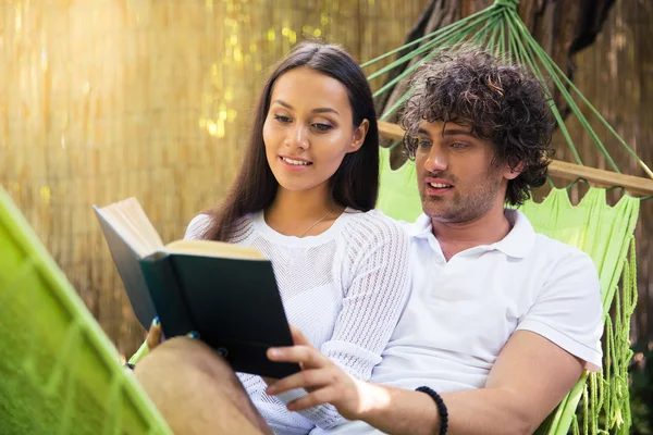 Smiling couple reading book together outdoors — Stock Photo, Image