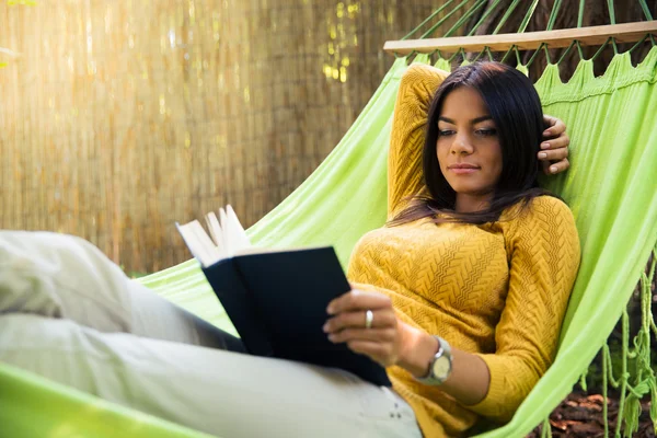 Mujer acostada en hamaca y leyendo libro — Foto de Stock