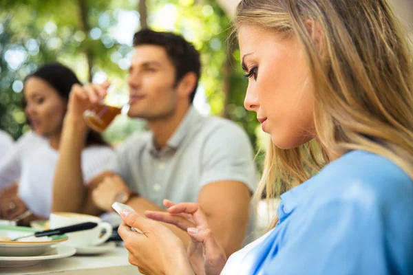 Frau benutzt Smartphone während sie im Restaurant sitzt — Stockfoto