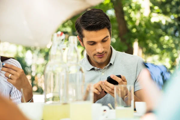 Hombre usando teléfono inteligente mientras está sentado en el restaurante al aire libre — Foto de Stock